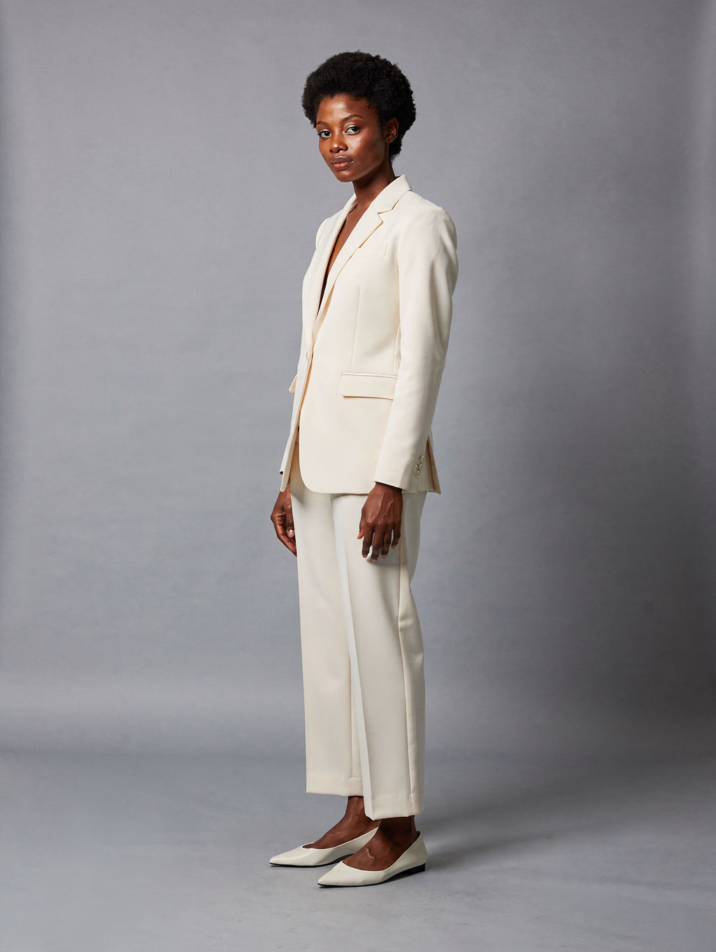 Model in an ivory trouser suit on grey seamless paper