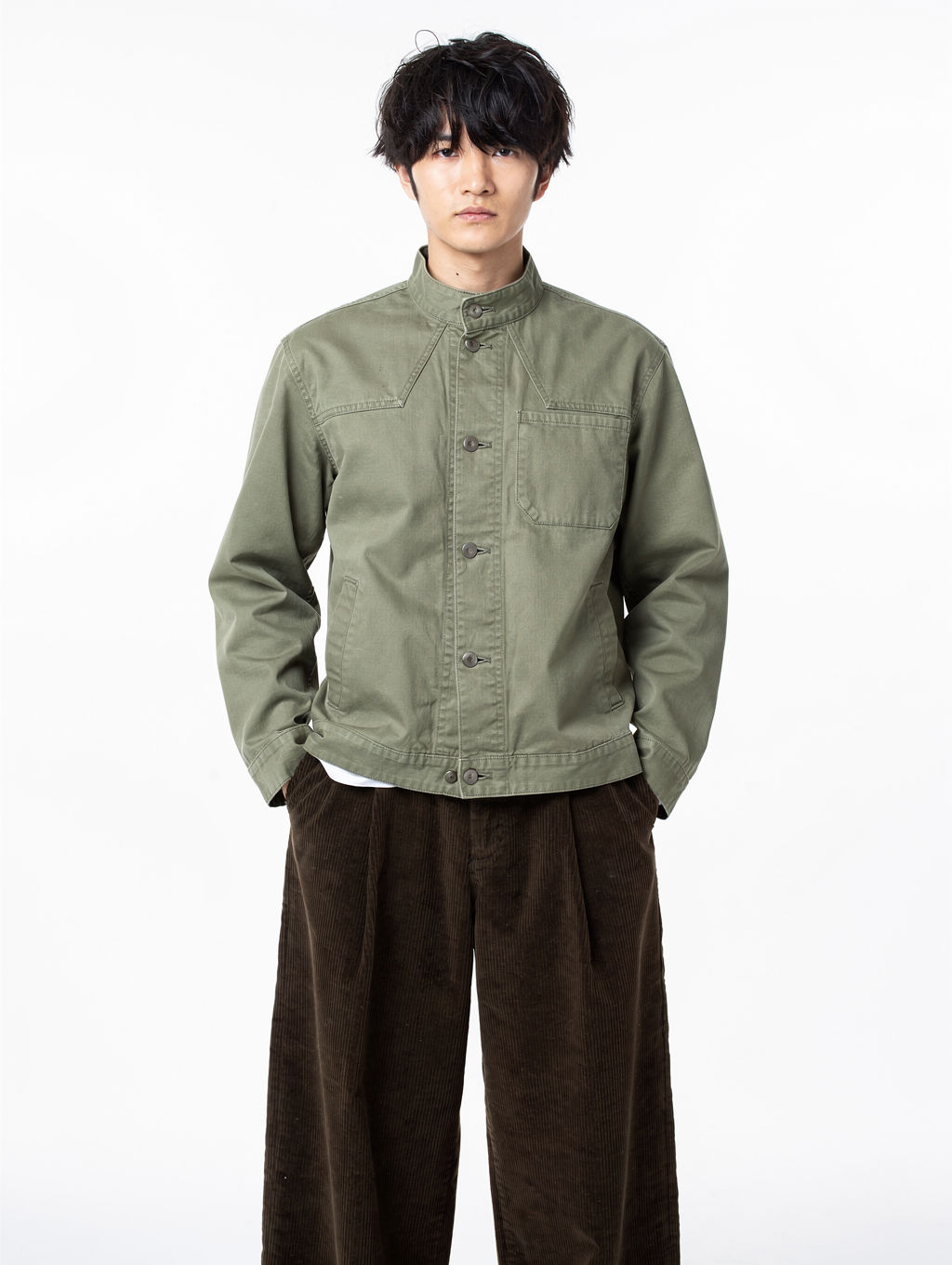 Model in a sage canvas work jacket on a white studio background